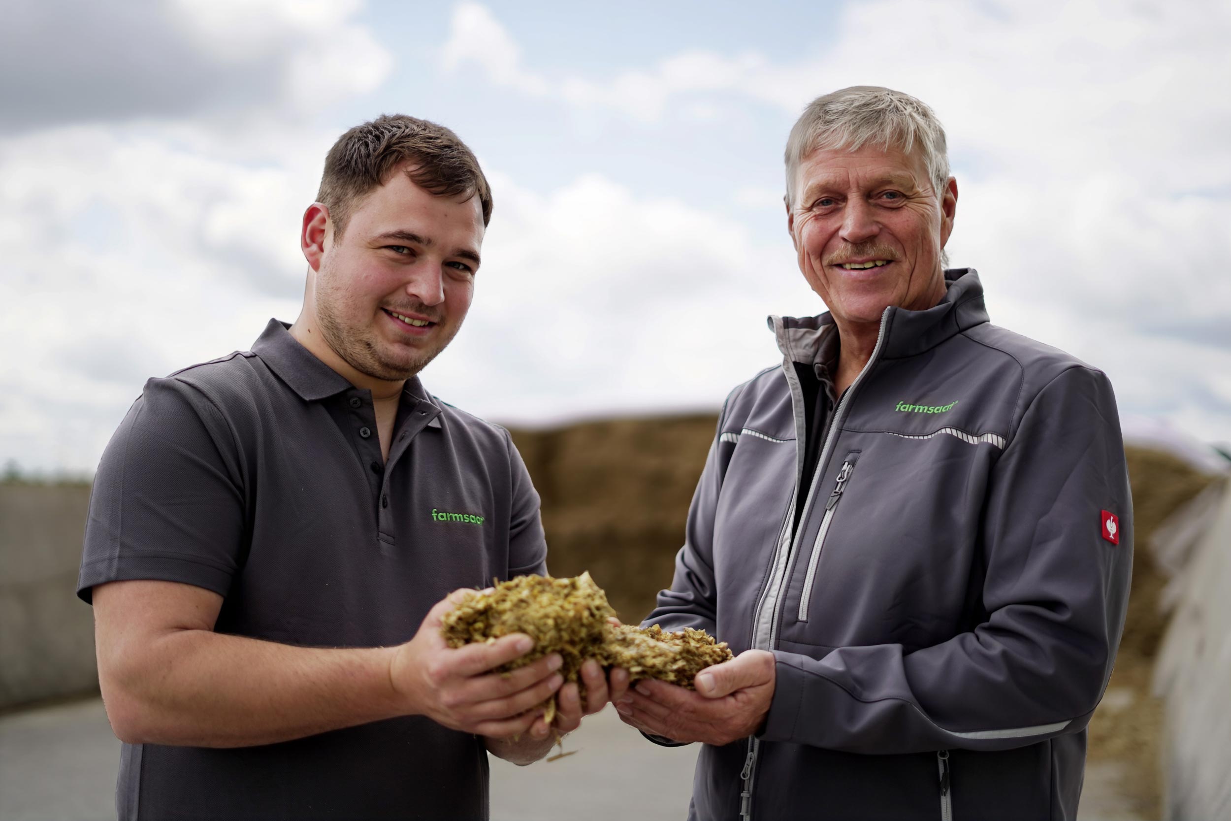 Zwei farmsaat-Mitarbeiter mit Maissilage in den Händen