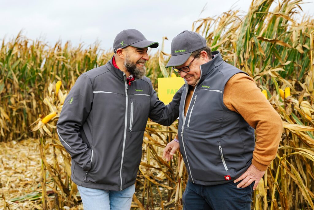 Zwei gut gelaunte Mitarbeitende auf in einem Maisfeld