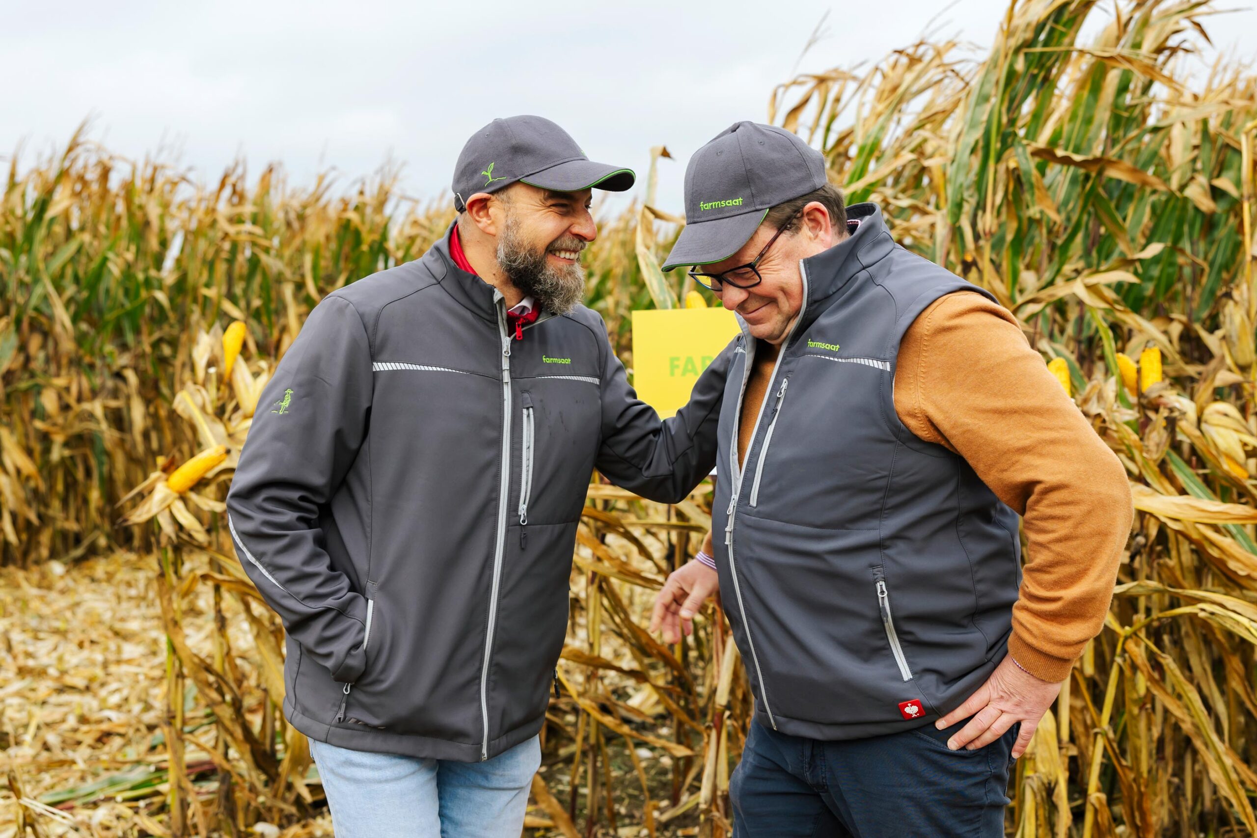 Zwei gut gelaunte farmsaat-Mitarbeitende auf in einem Maisfeld