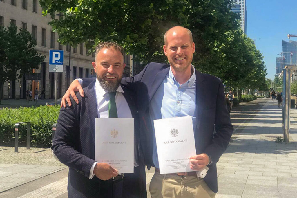 Zwei Farmsaat-Mitarbeiter halten eine polnische notarielle Urkunde in den Händen